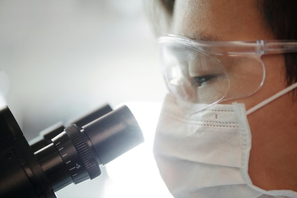 Close-up of a scientist wearing protective gear examining samples in a laboratory setting.
